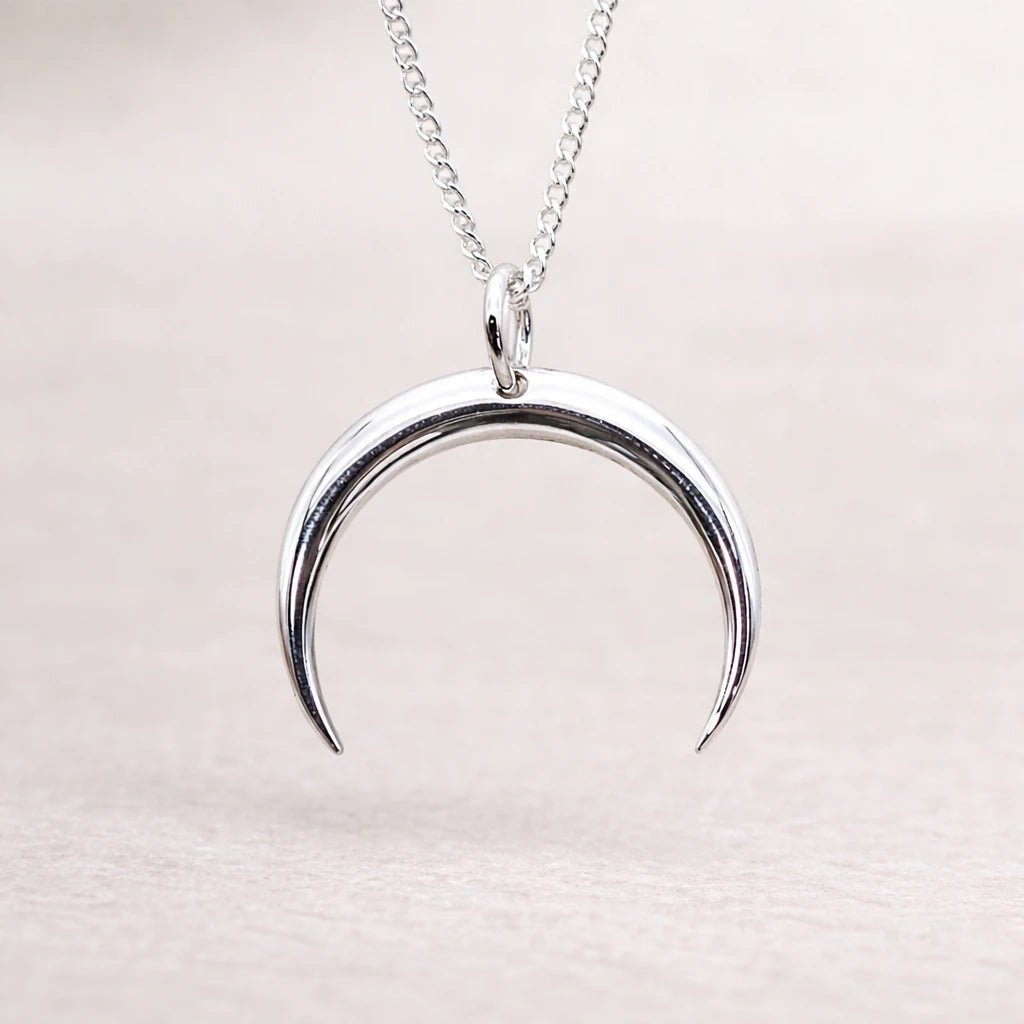 Silver crescent moon necklace on a light background
