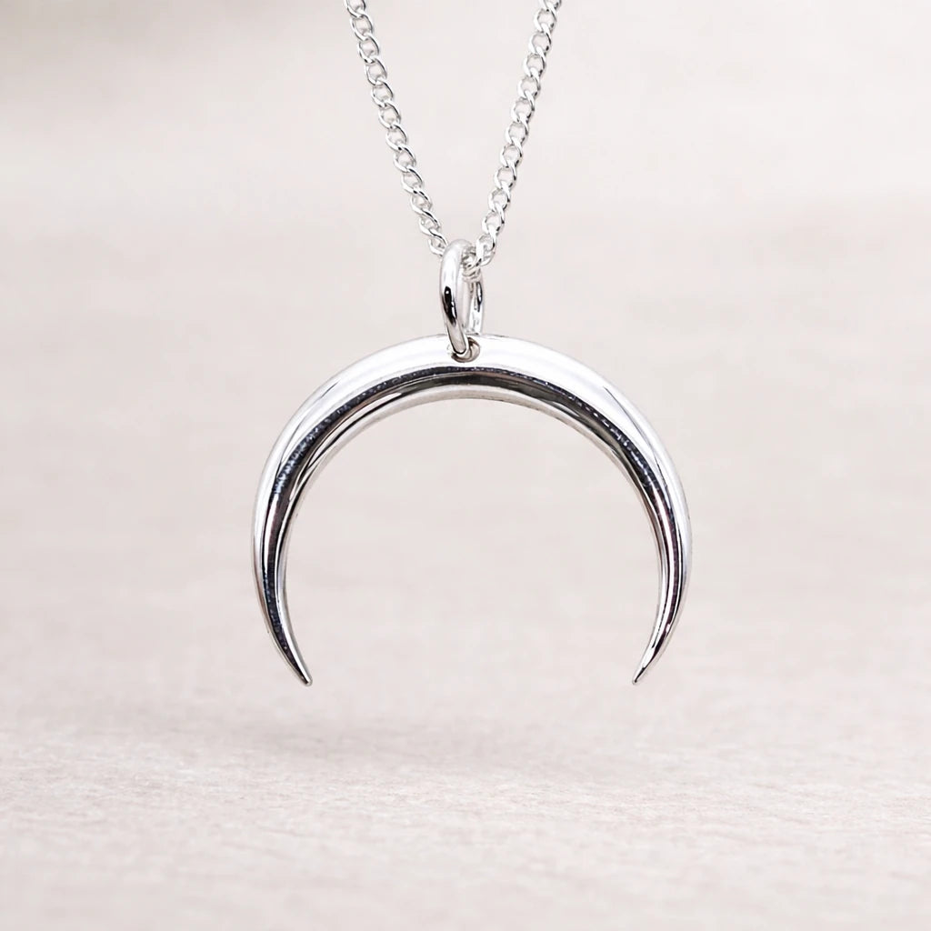 Silver crescent moon necklace on a light background