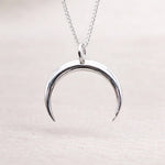 Silver crescent moon necklace on a light background