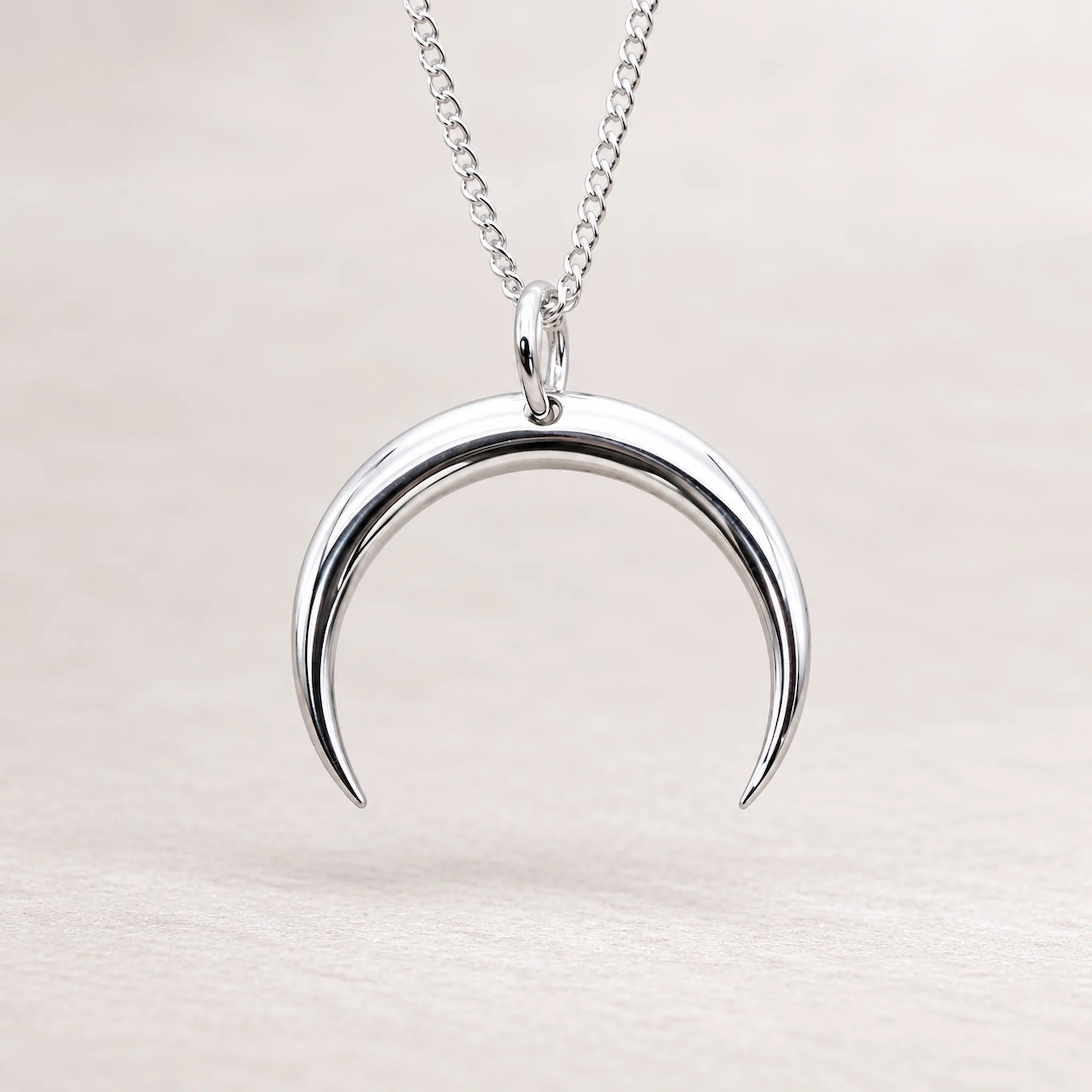 Silver crescent moon necklace on a light background