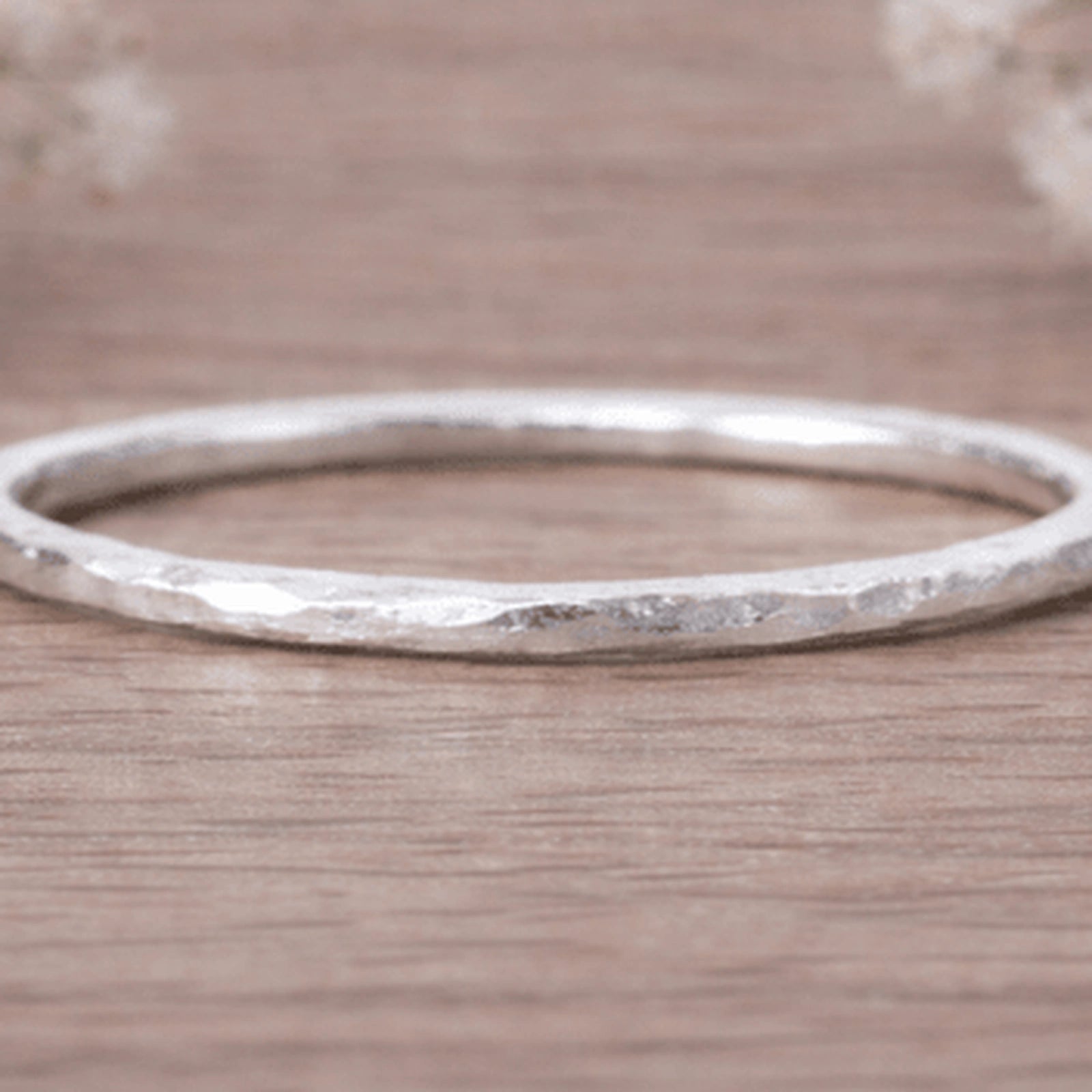 sterling Silver hammered stacker ring macro on a wooden surface
