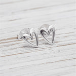 Silver heart-shaped earrings on a light wooden surface