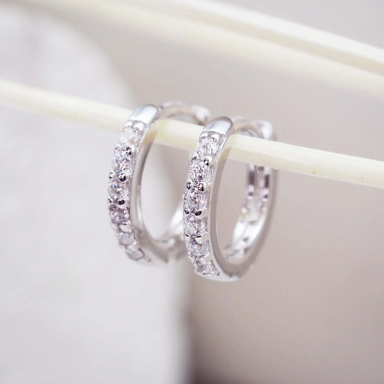 Classic Pavé Huggie Hoop Earrings featuring a polished silver hoop with a brilliant row of faceted cubic zirconia stones.