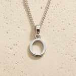 Sterling Silver Initial Necklace with a minimalist O charm pendant on a light stone background