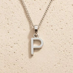 Sterling Silver Initial Necklace with a minimalist P charm pendant on a light stone background