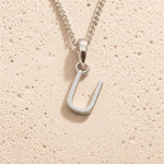 Sterling Silver Initial Necklace with a minimalist U charm pendant on a light stone background