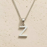 Sterling Silver Initial Necklace with a minimalist Z charm pendant on a light stone background