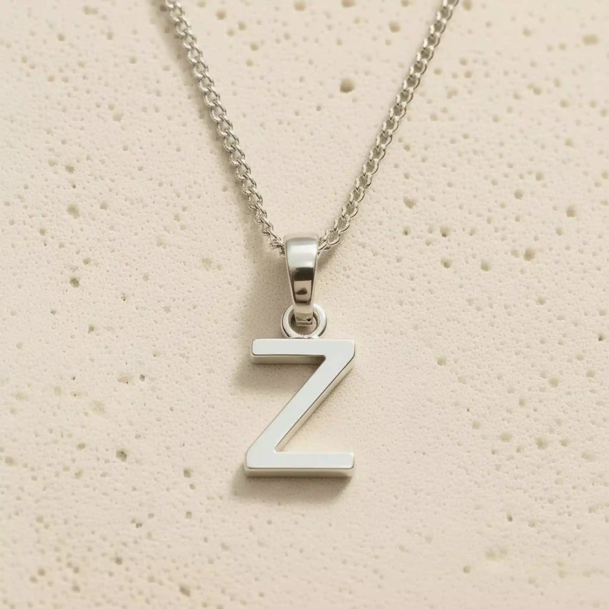 Sterling Silver Initial Necklace with a minimalist Z charm pendant on a light stone background