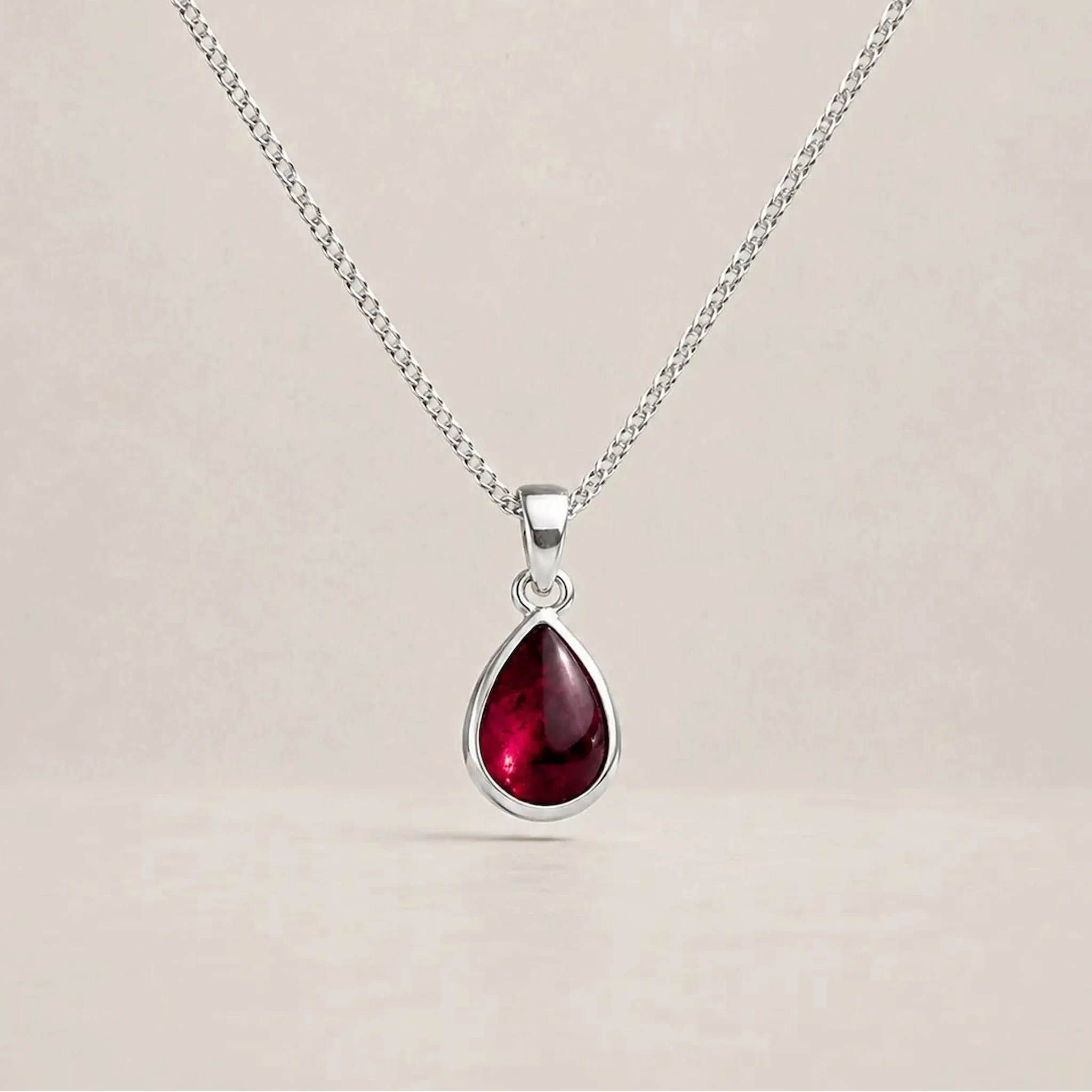 925 sterling silver January birthstone necklace with a deep red pear-shaped garnet pendant in a smooth bezel setting on a fine curb chain