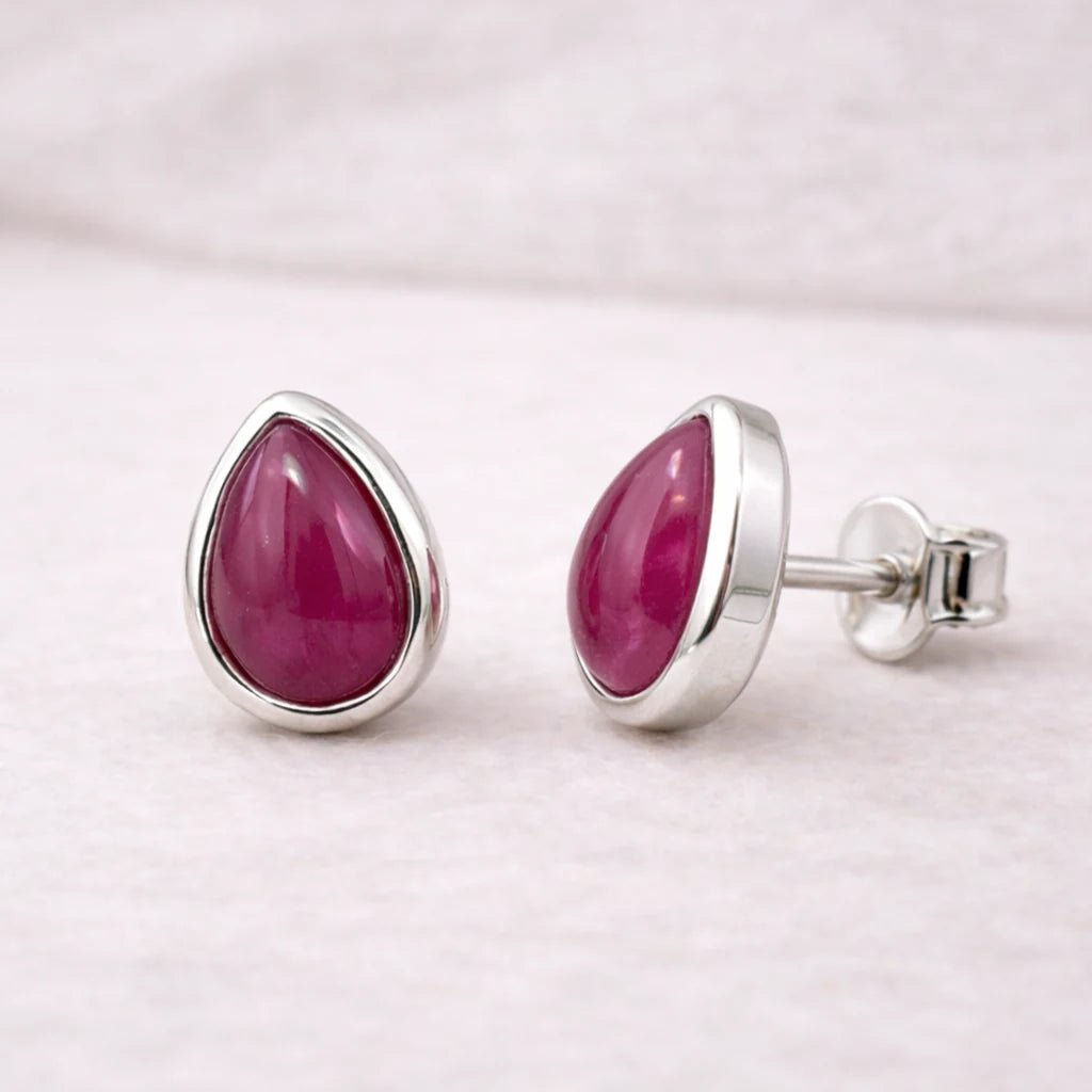 Pair of sterling silver earrings with natural ruby gemstones on a light gray background