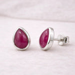 Pair of sterling silver earrings with natural ruby gemstones on a light gray background