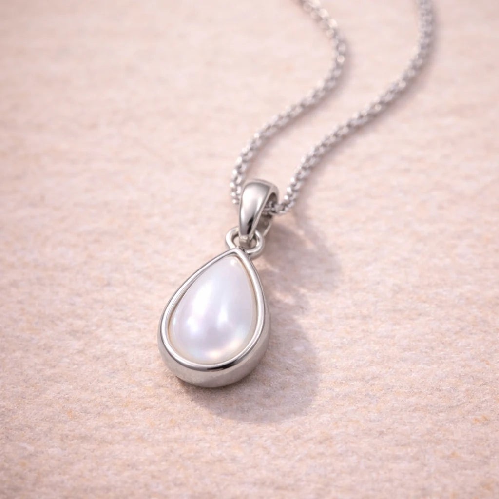 Teardrop-shaped natural mother of pearl pendant sterling silver necklace on a soft pink background