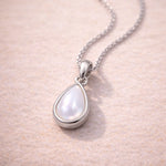Teardrop-shaped natural mother of pearl pendant sterling silver necklace on a soft pink background
