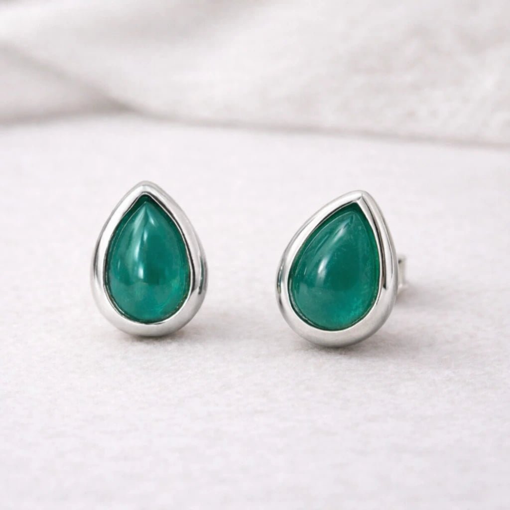 Teardrop-shaped green natural emerald gemstone earrings with sterling silver settings on a white background