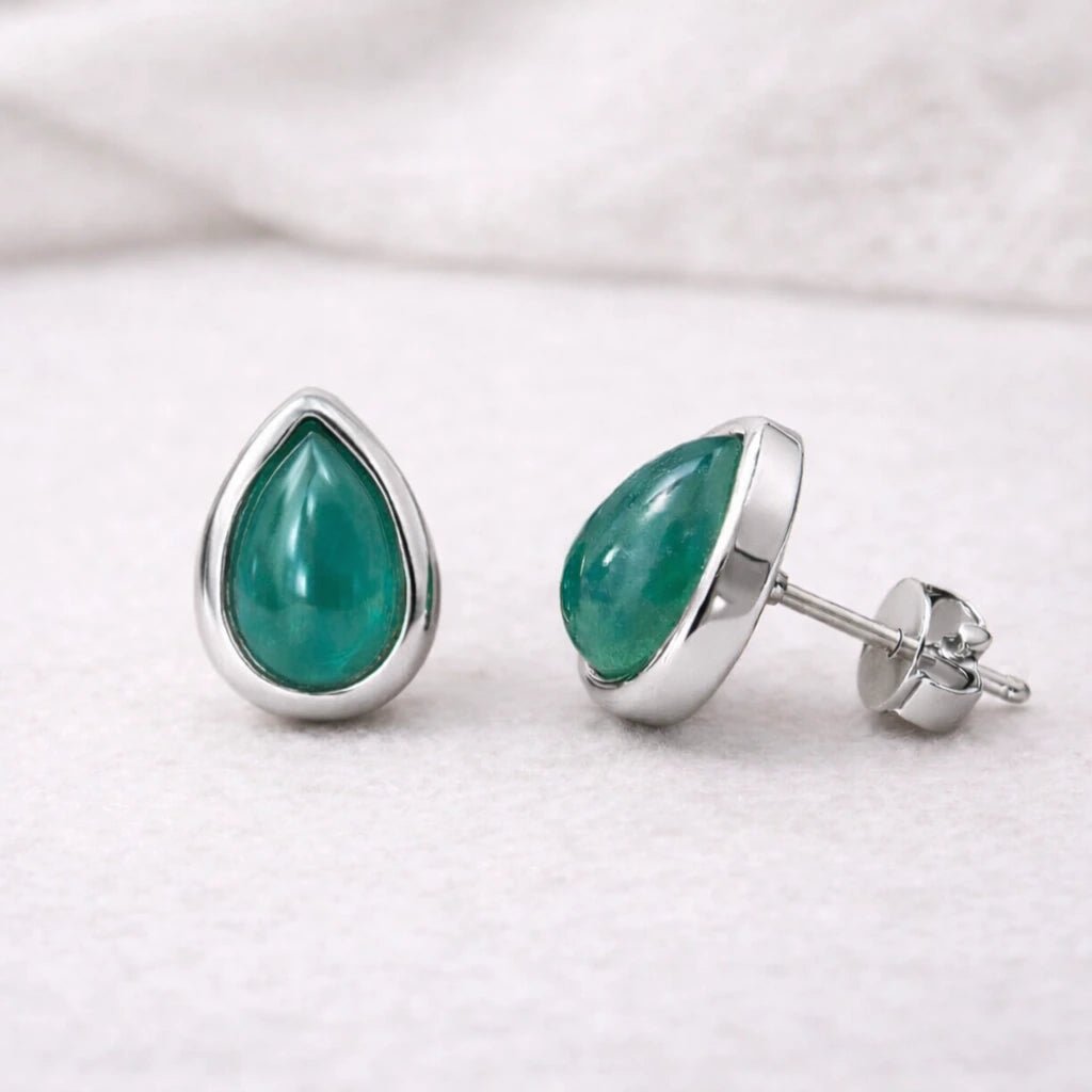 Teardrop-shaped green natural emerald gemstone stud earrings with sterling silver settings on a white background