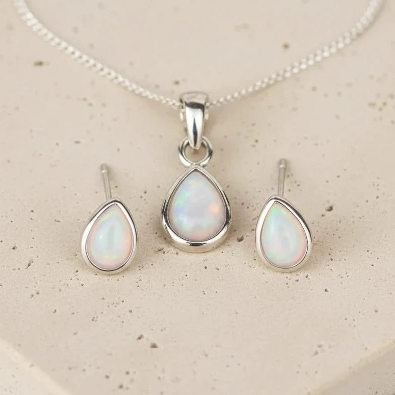 Sterling silver Opal pendant set with necklace and earrings on a beige stone surface