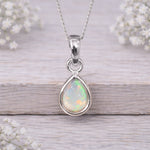 Opal pendant necklace on a wooden surface with flowers