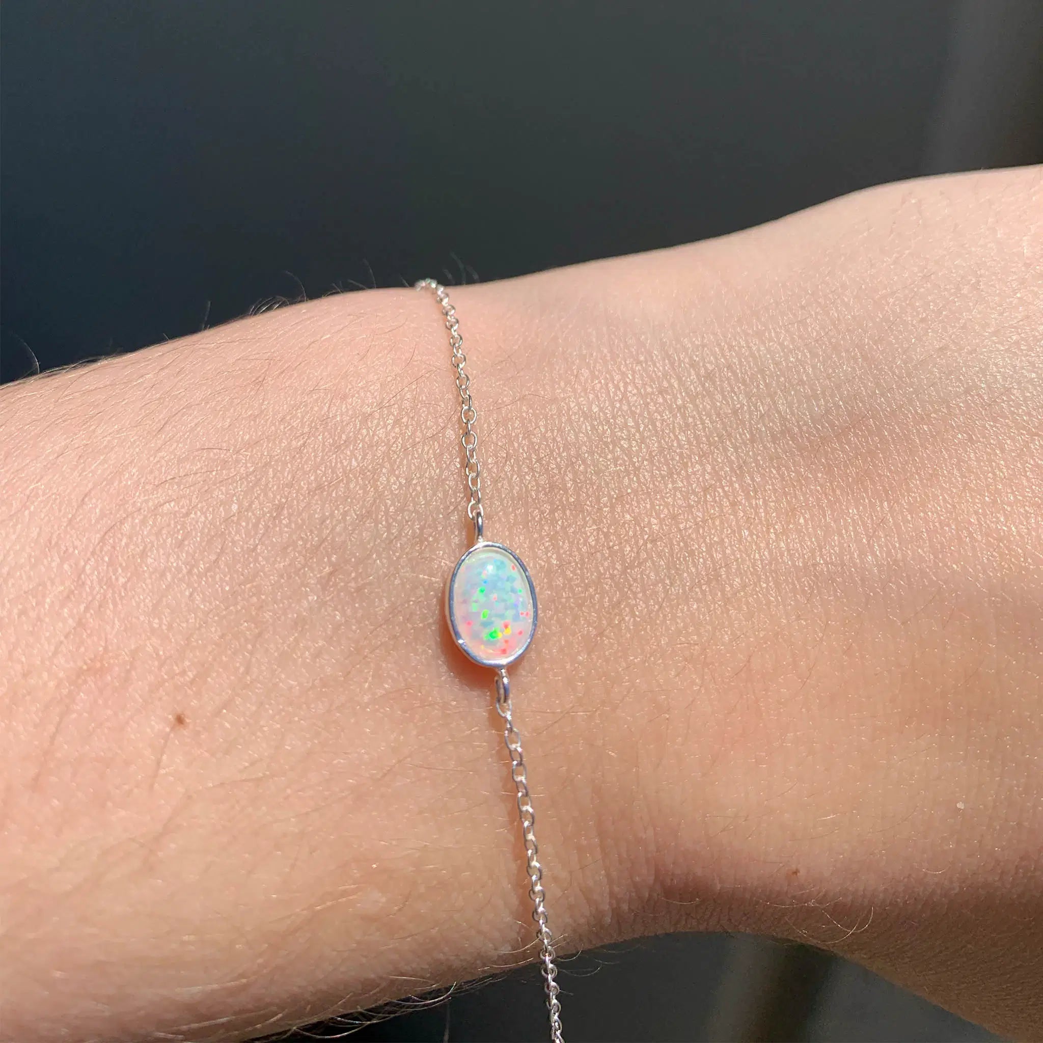 Sterling Silver chain bracelet with an opal stone on a wrist against a dark background