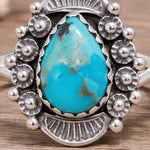 Silver ring with a large turquoise stone on a wooden surface
