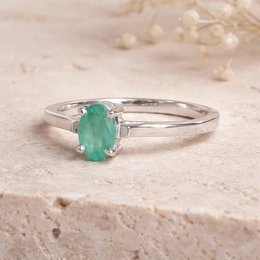 Sterling Silver ring with a oval solitaire claw set natural emerald gemstone on a light background