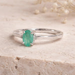 Sterling Silver ring with a oval solitaire claw set natural emerald gemstone on a light background