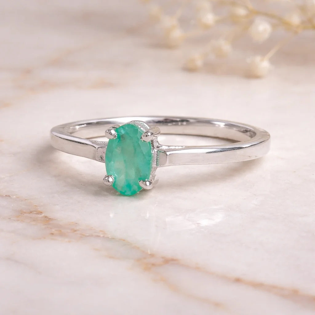 Sterling Silver ring with a oval solitaire claw set natural emerald gemstone on a light background