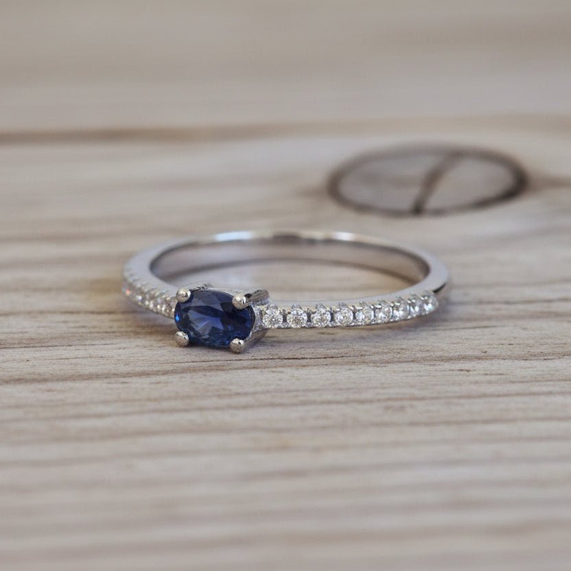 sterling Silver ring with a blue sapphire gemstone and small cubic zirconias on a wood surface