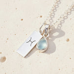 Sterling Silver necklace with a March Birthstone aquamarine pendant and a Pisces Zodiac Star Sign on a white background