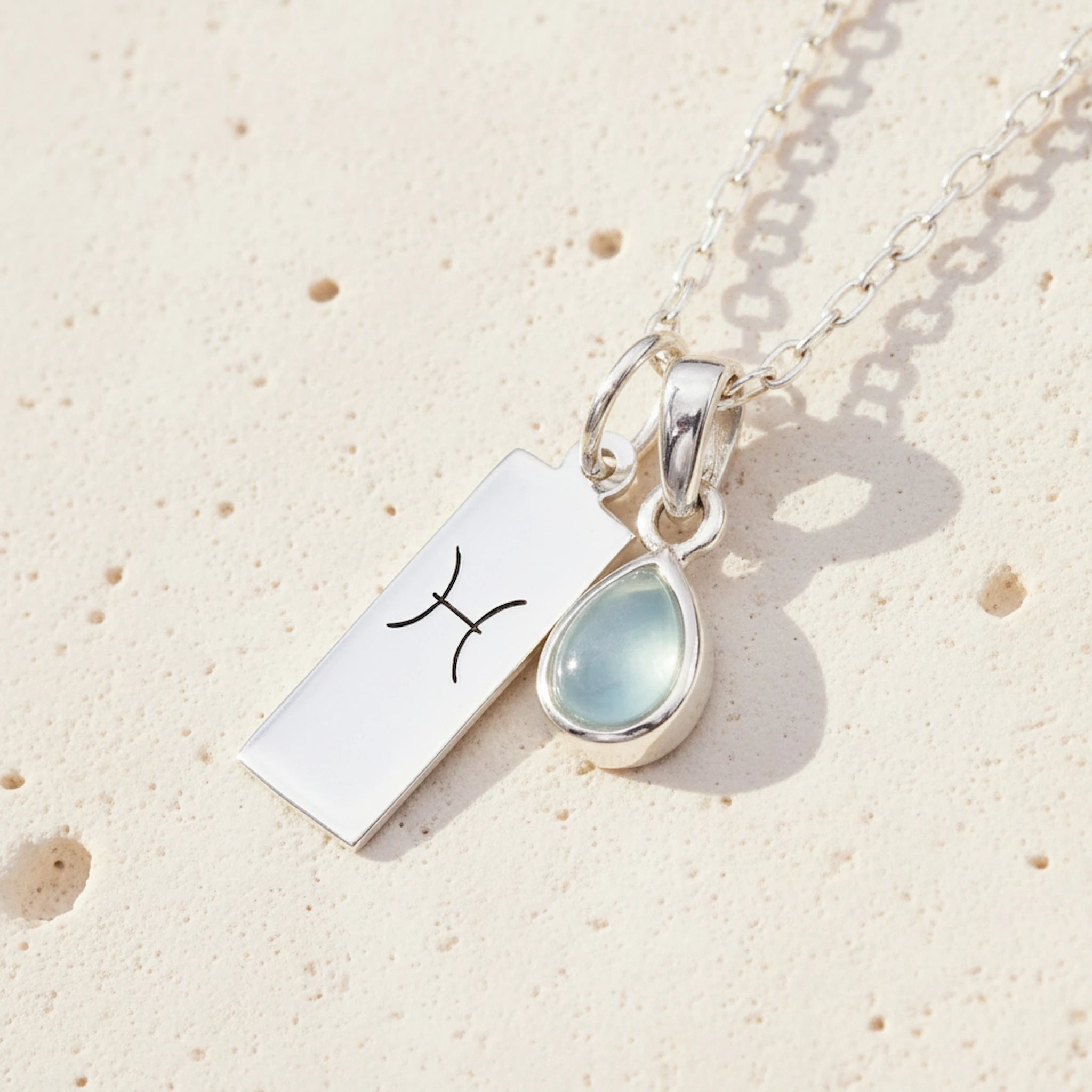 Sterling Silver necklace with a March Birthstone aquamarine pendant and a Pisces Zodiac Star Sign on a white background