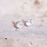 Pair of sterling silver stud earrings with a natural rainbow moonstone gemstones on a light background