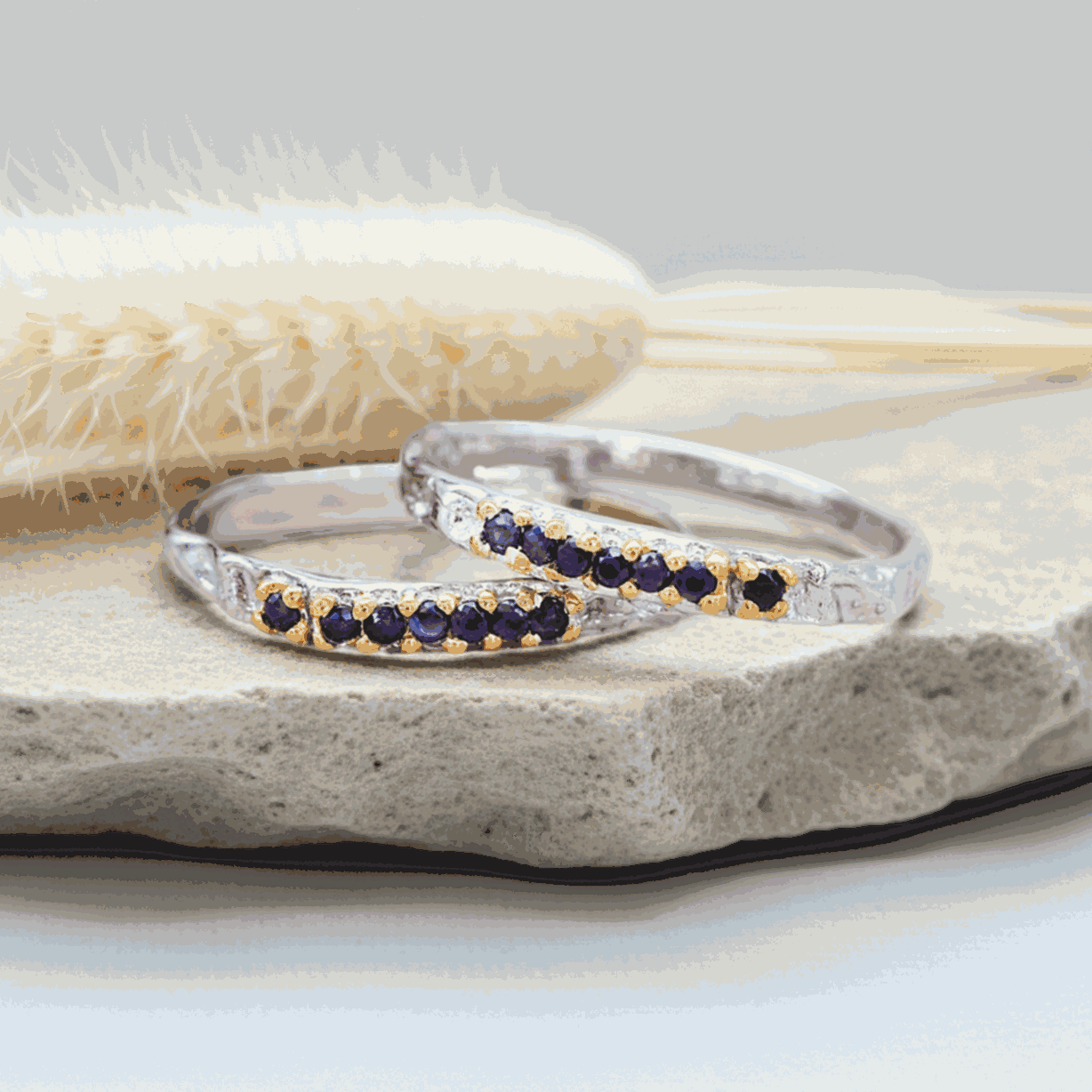 two Silver rings with natural sapphire gemstones on a stone surface