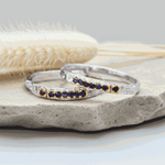 two Silver rings with natural sapphire gemstones on a stone surface