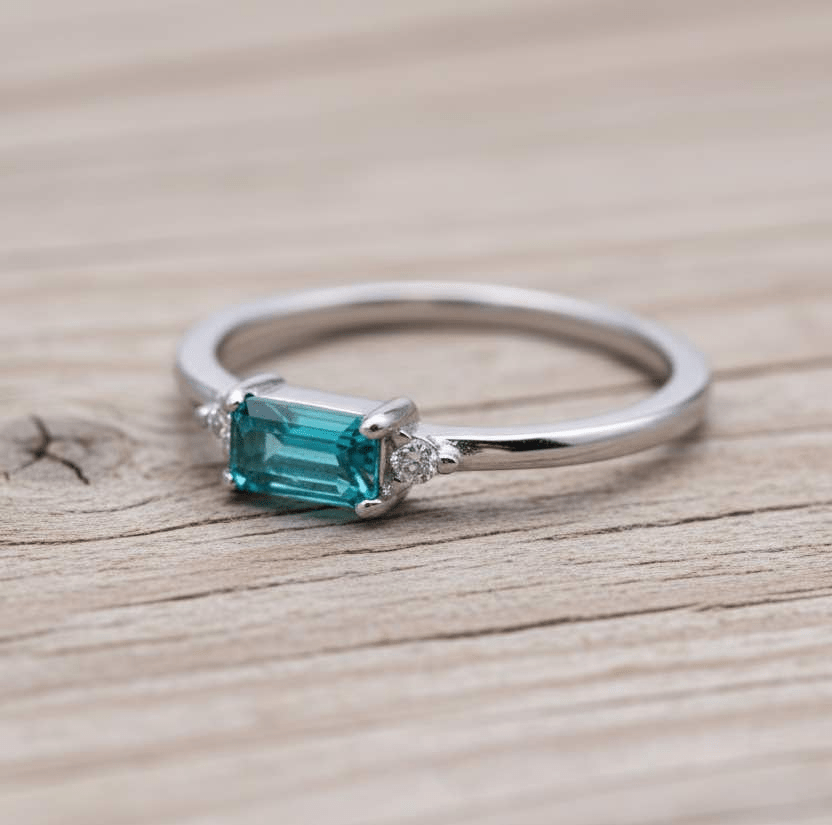 Dainty sterling silver gemstone ring with rectangular blue green tourmaline centre stone, round cubic zirconia side accents, and slim polished stackable band