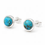 A pair of sterling silver stud earrings featuring round turquoise cabochons with natural matrix patterns, displayed on a clean white background.