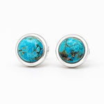 A pair of silver stud earrings with round turquoise cabochon stones, displayed on a clean white background.