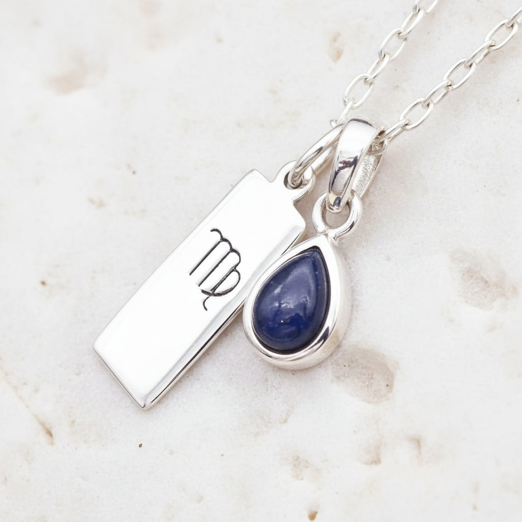 Sterling Silver necklace with a blue teardrop natural sapphire pendant and virgo zodiac pendant on a textured background