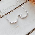 Sterling Silver wave necklace on a wooden surface