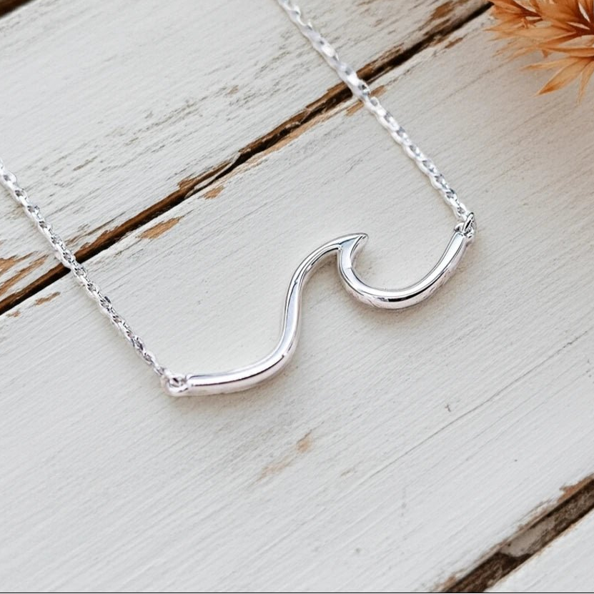 Sterling Silver wave necklace on a wooden surface