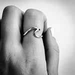black and white image of a sterling silver wave ring worn on a finger