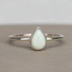 sterling Silver ring with a teardrop-shaped white opal stone on a neutral background