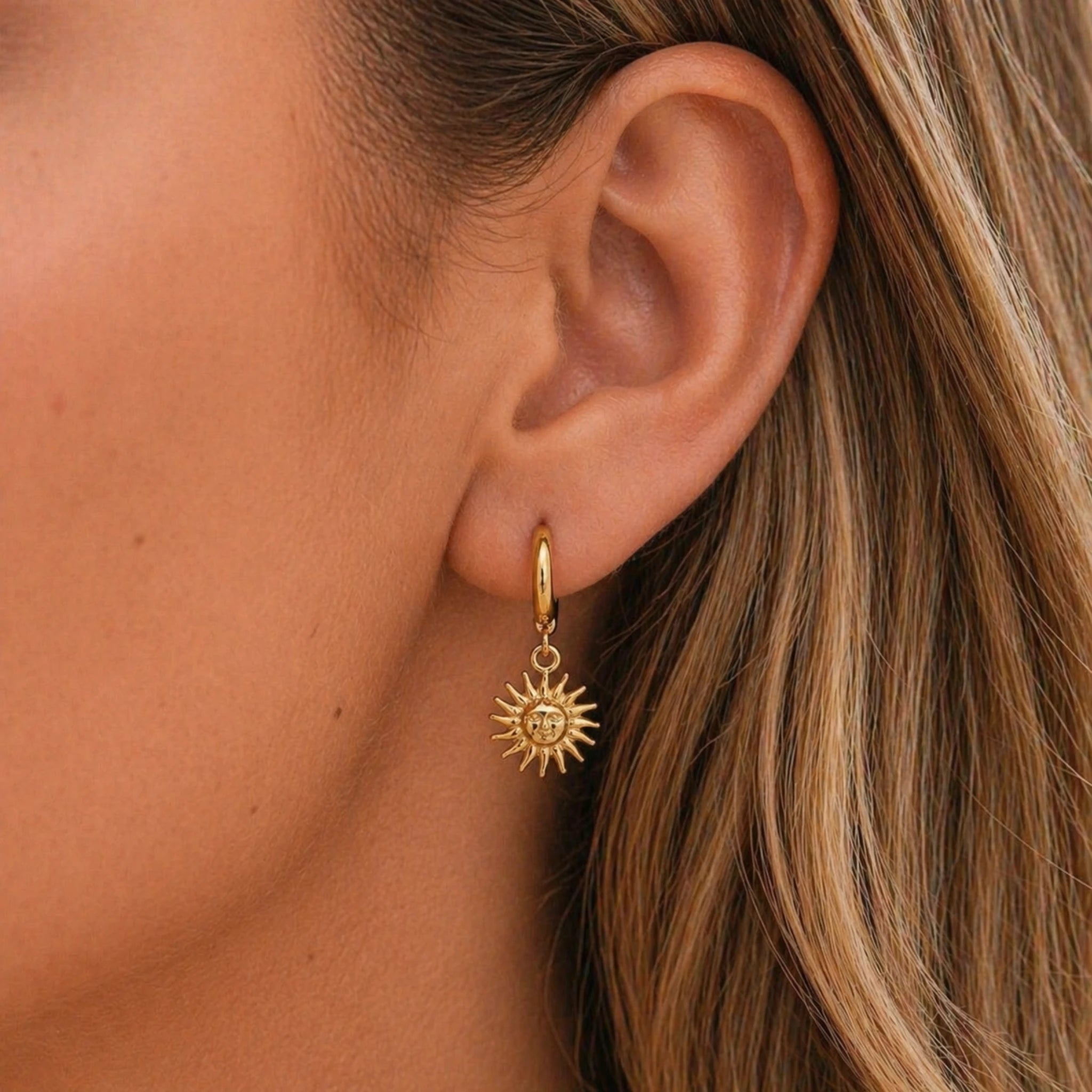 waterproof stainless steel sunburst charm gold huggie earrings being worn