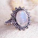 Silver ring with a teardrop-shaped moonstone gemstone on a textured white background