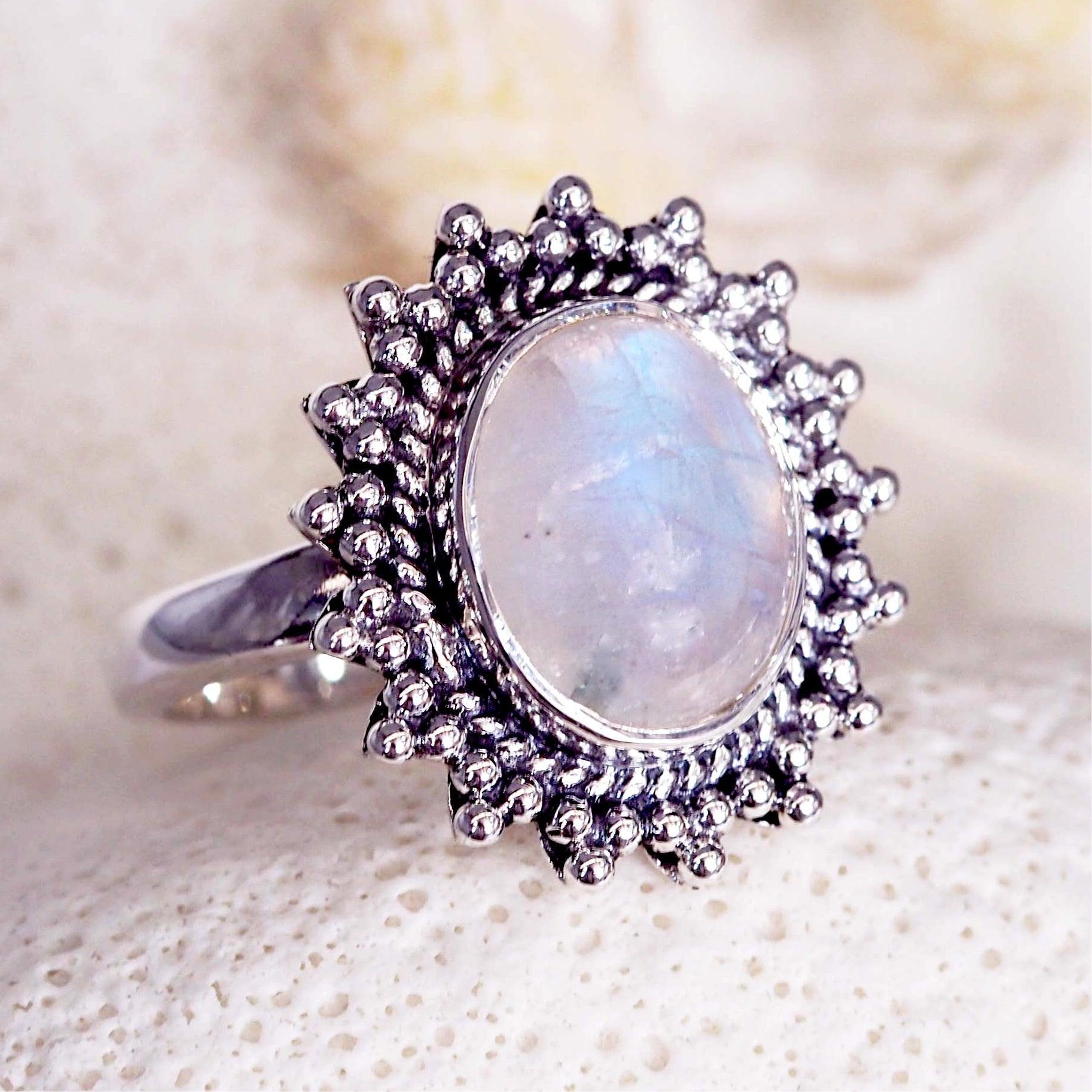 Silver ring with a teardrop-shaped moonstone gemstone on a textured white background
