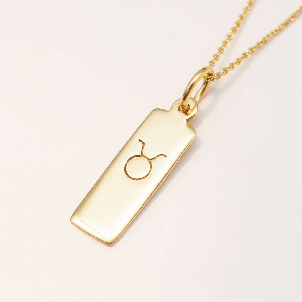 Gold taurus zodiac necklace on a white background