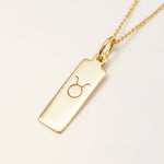 Gold taurus zodiac necklace on a white background
