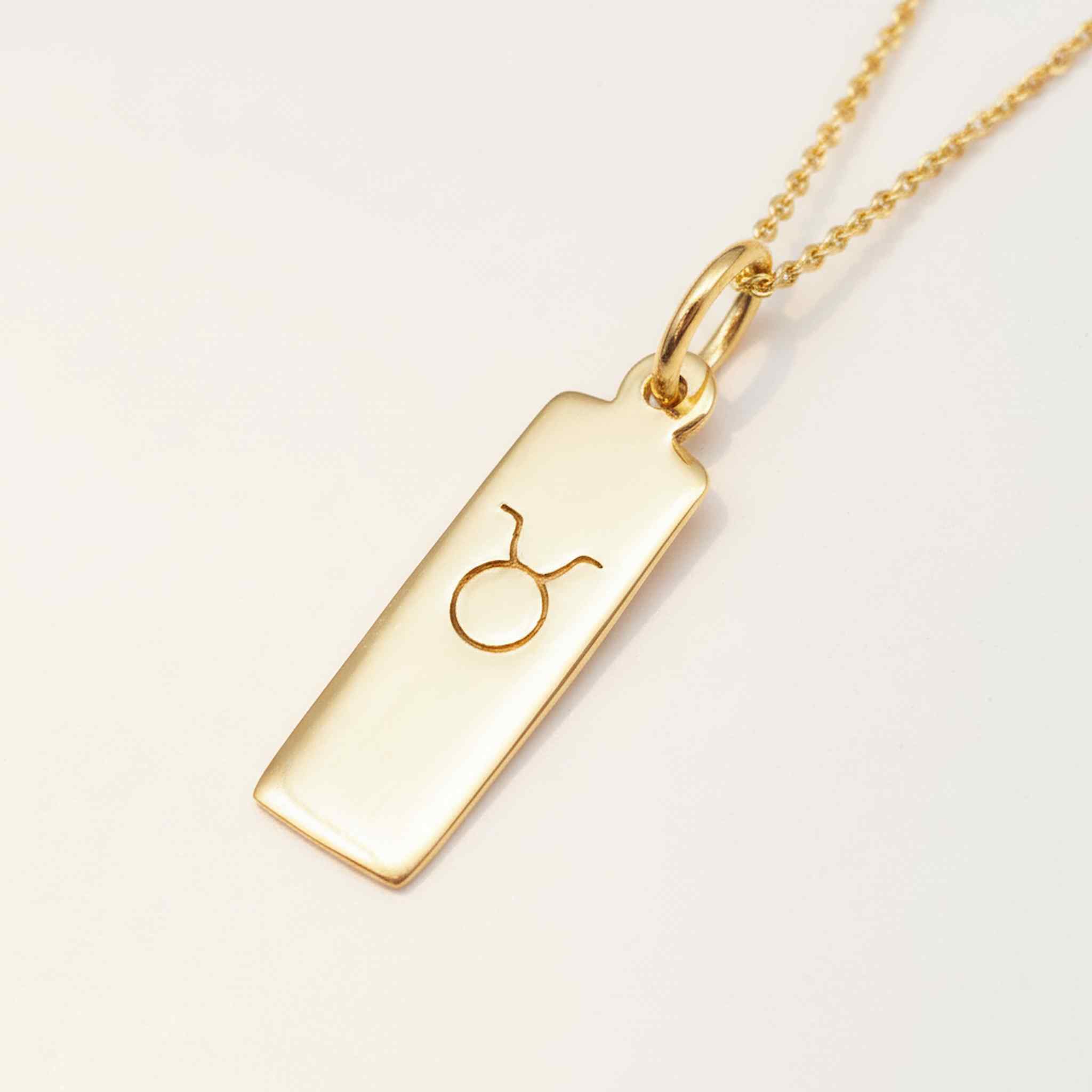 Gold taurus zodiac necklace on a white background