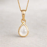 Gold pendant with a pearl gemstone on a light gray background