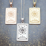 Three tarot card pendants on necklaces in Rose Gold, Silver and Gold against a textured blue background