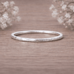 Silver ring on a wooden surface with delicate flowers in the background