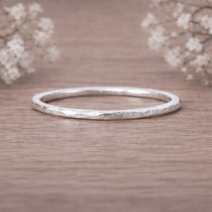 Silver ring on a wooden surface with delicate flowers in the background